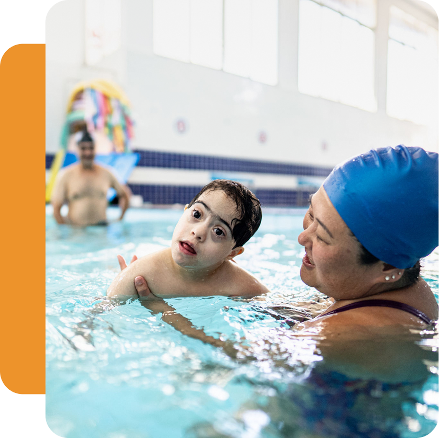 Child swimming with instructor in pool.