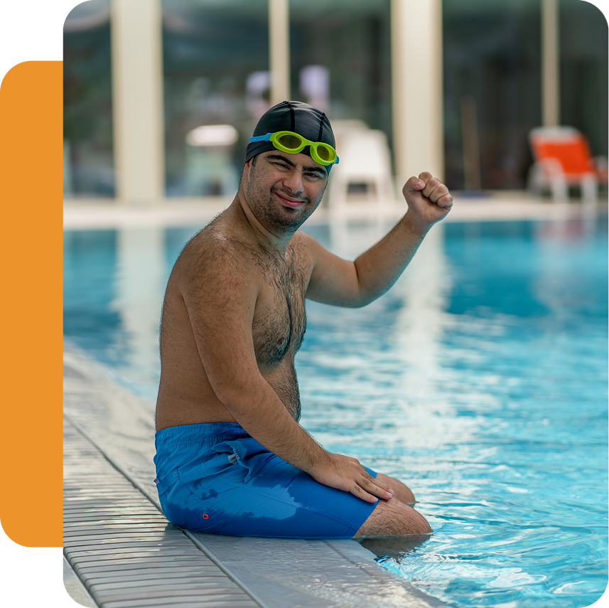 Man sitting by the pool, wearing goggles.